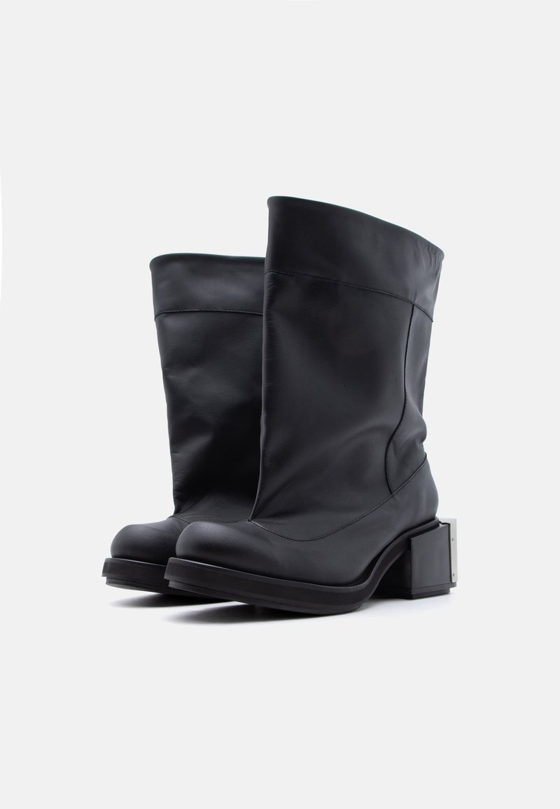 Coppia di stivali neri di pelle fino a metà polpaccio con punta quadrata e tacchi a blocco, mostrati affiancati su uno sfondo bianco.