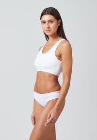 Witte katoenen sportbeha met brede schouderbanden en naadloos ontwerp, gecombineerd met bijpassende low-rise bikini slipjes. Soepele textuur, minimalistische stijl.