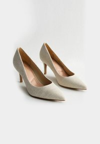 Décolleté beige a punta con tomaia in tessuto testurizzato, fodera interna liscia e sottile tacco in legno. Design semplice, senza motivi visibili.