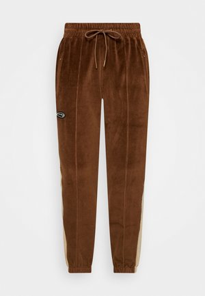 Bruine velours joggerbroek met elastische tailleband, trekkoord, zijzakken, beige zijstrepen en een klein zwart logopatch op de linker dij.