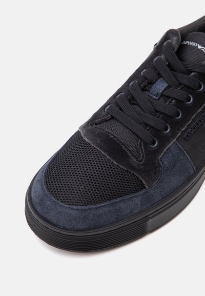 Baskets noires et bleu foncé avec embout en mesh, superpositions en daim et velours, lacets noirs et semelle en caoutchouc.