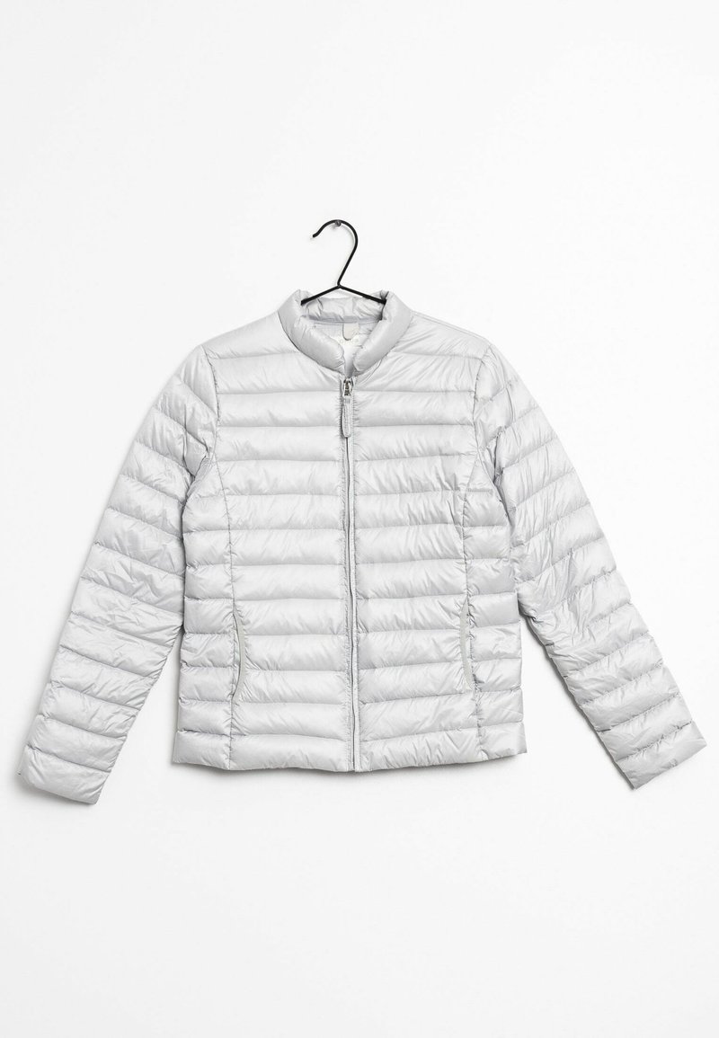 Veste matelassée grise claire avec manches longues et fermeture éclair à l'avant, suspendue à un cintre noir sur fond blanc.
