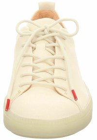 Cremfarbene Sneaker aus glattem Leder. Mit abgerundeter Zehenpartie, flachen Schnürsenkeln und roten Akzenten an den Seiten. Subtile Textur sichtbar.