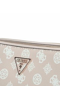 Portafoglio rosa con una superficie decorata, caratterizzato da un lucido logo triangolare Guess. Chiusura con zip e materiale testurizzato.