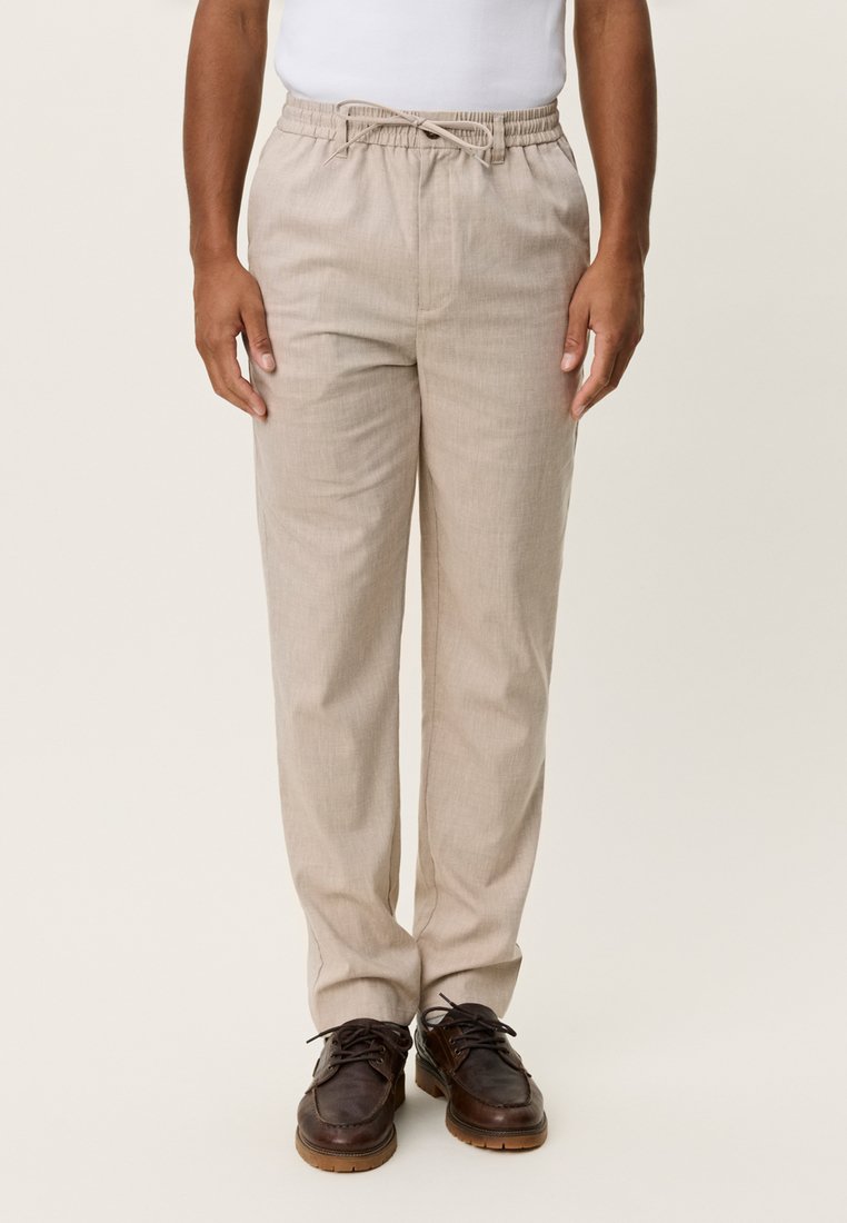 Pantalon en mélange de lin beige avec une taille élastique et un cordon de serrage, présentant une coupe décontractée et une jambe droite. Pas de poches visibles.
