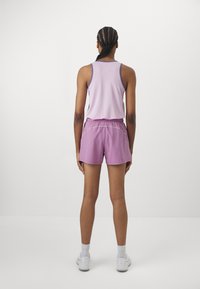 Lys lilla tanktopp med tynne stropper, sammen med matchende lilla shorts med elastisk liv og hvite detaljer.