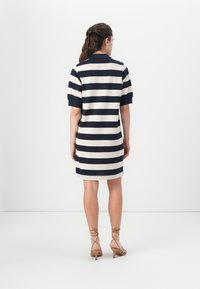 Ριγέ φόρεμα σε ναυτικό και κρεμ χρώμα, κοντά μανίκια, κολάρο, μήκος έως το γόνατο, φτιαγμένο από μαλακό υλικό, με εφαρμοστή σιλουέτα και μινιμαλιστικό σχέδιο.