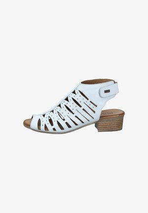 White leather open-toe sandal with cut-out patterns, low stacked wooden heel, and ankle strap with Velcro closure.