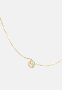 Guldhalsband med en cirkulär hänge med stjärnmotiv, omgivet av klara kristaller för extra detalj. Fina kedjelänkar.