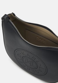 Black leather bag with a curved shape, featuring a perforated logo design and silver zipper. Interior has a tan lining and card slot.