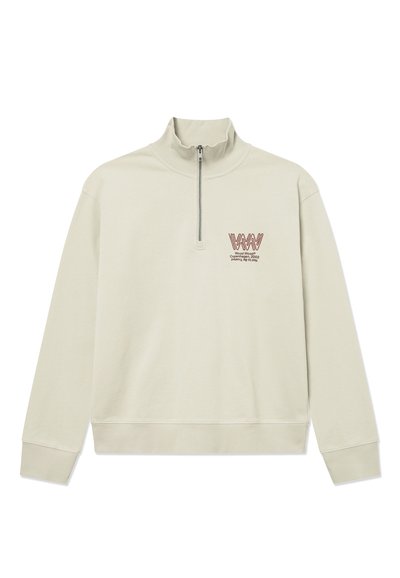 Pullover lungo beige chiaro con maniche a raglan, polsini e orlo a coste, mezza cerniera e piccolo logo rosso con testo sul petto a sinistra.