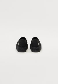 Scarpe espadrillas nere con tomaia in tessuto e suole in iuta intrecciata. Presentano un tallone basso e discreti dettagli del logo sui lati.