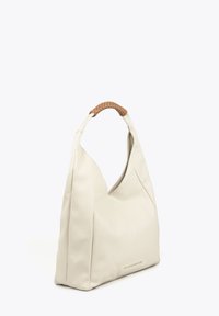 Sac hobo en cuir crème avec une finition texturée et une anse tressée en tan. Il présente une forme arrondie et une fermeture éclair sur le dessus.