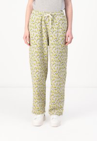 Grå joggerbyxor med banantryck, som har ett elastiskt midjeband med dragsnöre och en avslappnad passform. Matchas med vita sneakers.