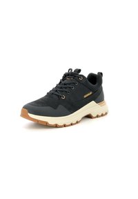 Zapatilla deportiva negra con parte superior texturada, entresuela beige y suela de goma. Presenta un cierre con cordones y un pequeño detalle del logo.