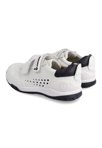 Zapatillas blancas con un acento de talón negro, con parte superior de cuero suave, diseño perforado transpirable y cierre de cinta de Velcro.