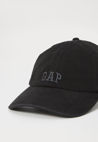 Fekete pamut baseball sapka, sötét szürke hímzett "GAP" logóval, ívelt karimával és hátul állítható pánttal. Texturált anyagfelület.