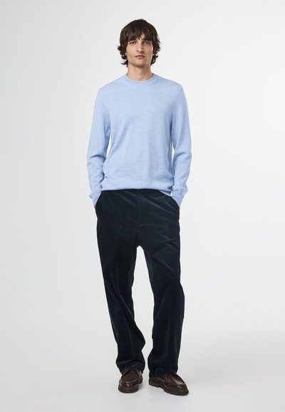 Light blue long-sleeve sweater, soft texture, paired with dark navy corduroy pants, relaxed fit, accentuated pockets, and brown leather shoes.