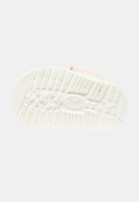 Sole di scarpa in gomma bianca con motivo di presa testurizzato, decorata con motivi floreali e logo "Dude", con un leggero bordo rosa visibile.