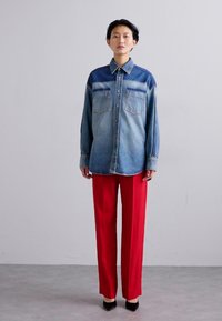 Denim särk, millel on gradientne sinine disain ja kaks rinnataskut. Kombineeritud kõrgema vöökohaga punaste pükstega ja mustade kontsadega.