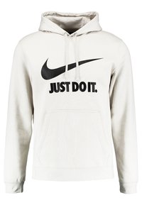 Ljusgrå hoodie i mjukt tyg, med en svart Nike swoosh-logotyp och texten "JUST DO IT." Inkluderar en framficka och dragsko vid huvan.