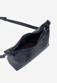 Melnas ādas soma ar rāvējslēdzēja aizdari, taisnstūra forma, plāns siksniņa un gluda tekstūra. Interjers ar brūnu oderi.