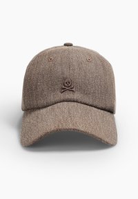 Gorra marrón hecha de un tejido texturizado, con un emblema elevado de calavera y huesos cruzados. Visera curva clásica, diseño de seis paneles con ventilaciones de ojales.