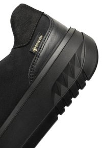Zapatilla negra de GORE-TEX con parte superior de cuero liso, acentos de textil y suela de goma texturizada con patrón de dibujo geométrico.