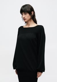 Μαύρο μακρυμάνικο τοπ από απαλό ύφασμα, με φαρδύ λαιμόκοψη σκάφος, σούρα στο μπούστο και στενά μανίκια. Λείο ύφασμα και άνετη εφαρμογή.