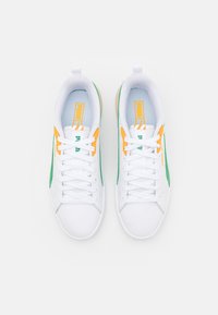 Baskets blanches avec des accents verts et orange, dotées d'une tige synthétique lisse, d'un design à lacets et d'un col rembourré pour le soutien.