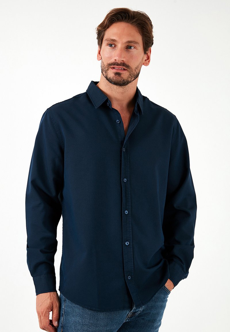 Camisa de botones de manga larga en azul marino, hecha de algodón, con cuello puntiagudo, cierre de botones y un corte relajado.