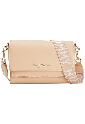 Beige læder crossbody taske med klaplukning, gyldent Tommy Hilfiger-logo og justerbar stofrem med teksten "Tommy Hilfiger" i hvid.