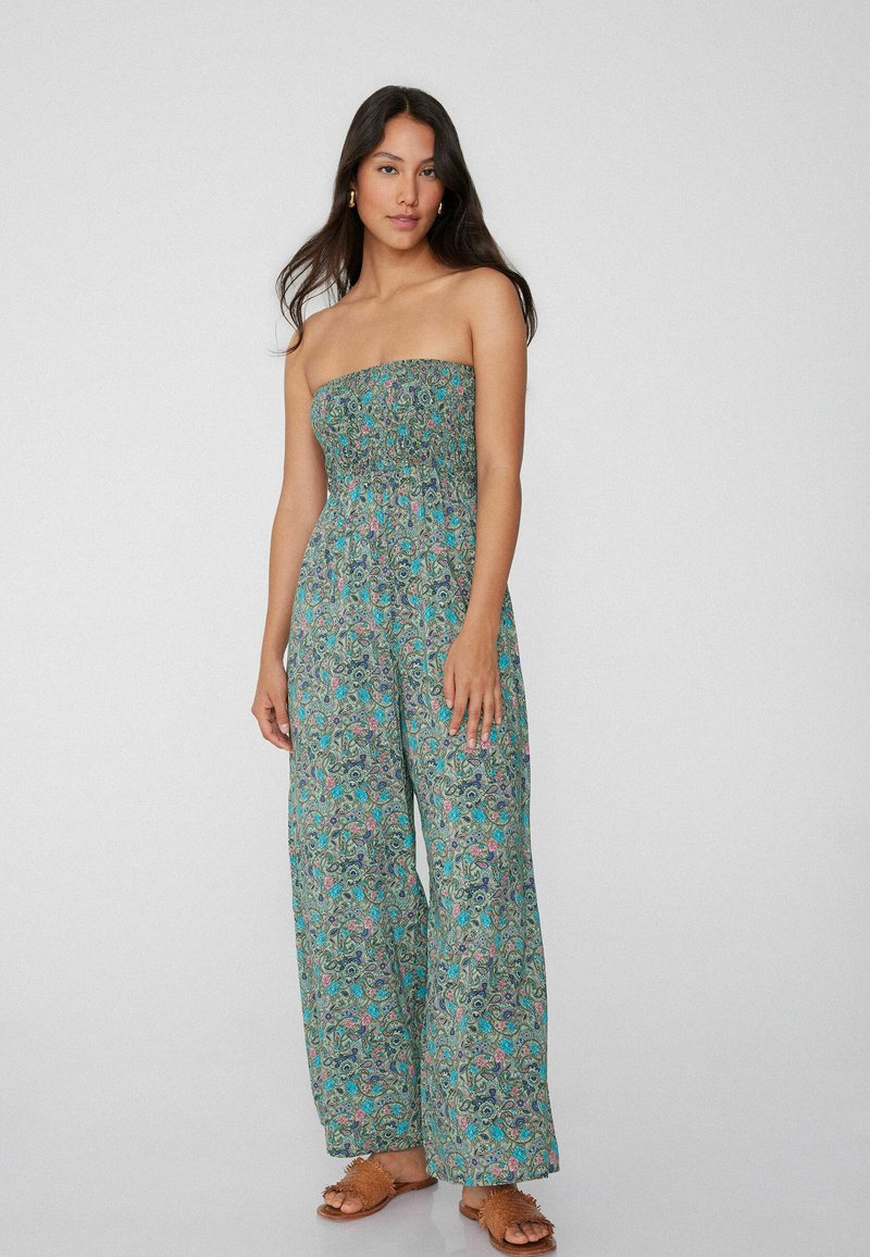 Mono verde sin tirantes con patrón floral, que presenta un cuerpo fruncido y piernas anchas y fluidas de tejido ligero.