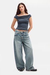 Modrá off-shoulder blúzka s drapovanou textúrou, skombinovaná so svetlomodrými širokými džínami. Džínsy majú klasický dizajn s piatimi vreckami.