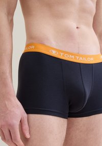 Fekete pamut bokszernadrág narancssárga rugalmas derékkal, amelyen a "TOM TAILOR" logó található. Az anyag sima, feszes illeszkedésű.