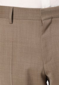 Pantaloni marroni chiari realizzati in tessuto texture con un sottile motivo a quadretti. Presentano una vita piatta e due tasche laterali.