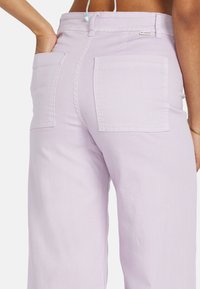 Pantalones de mezclilla lila de pierna ancha con dos bolsillos traseros y cintura alta, con un acabado de algodón texturizado y una pretina segura.