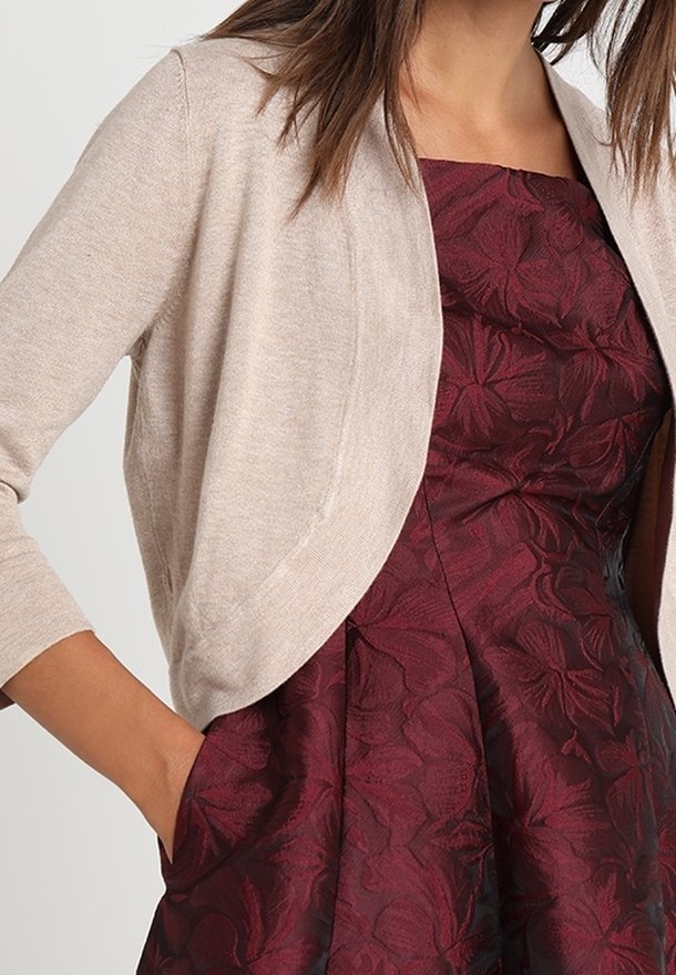 Beige cardigan with 3/4 sleeves, lightweight knit material, open front design, paired with a deep burgundy dress featuring floral patterns.