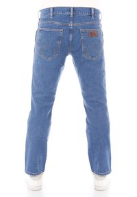 Jeans de mezclilla azul con un corte recto, que presentan dos bolsillos traseros con un diseño apuntado y una etiqueta de cuero.