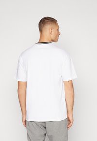 Hvit bomulls t-skjorte med rund halslinning som har svart detalj på kragen; avslappet passform og kortermet, enkel design.