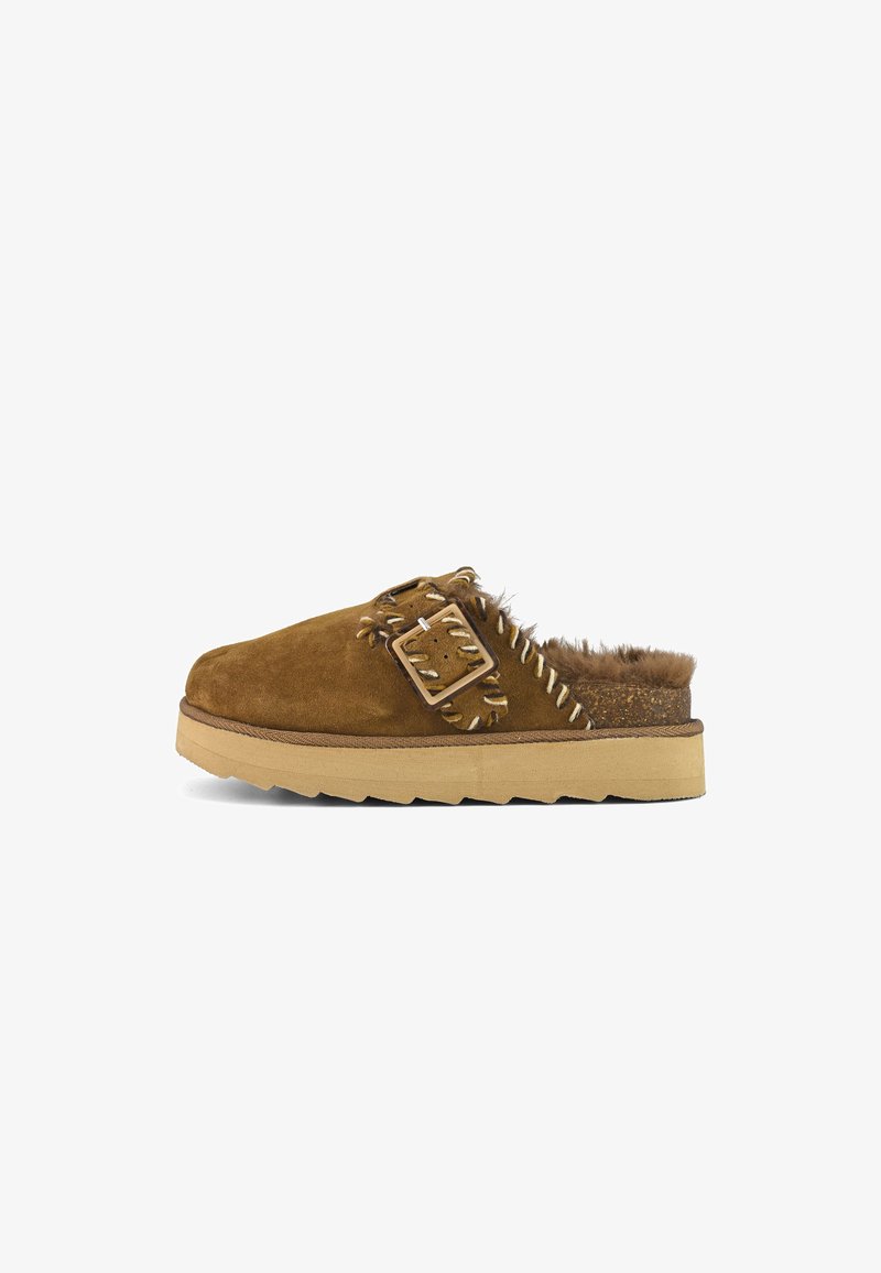 Pantofole in suede marrone con fodera in pelliccia, dettaglio con fibbia quadrata e cuciture decorate. Presentano una suola imbottita e una forma della punta arrotondata.