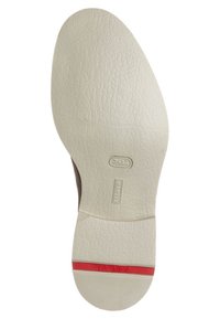 Suola di una scarpa beige chiaro con superficie texturizzata, striscia rossa vicino al tallone e marchi del brand in rilievo.