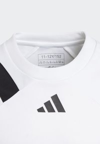 Weißes Sportshirt mit einem schwarzen Akzent an einer Schulter, das ein schwarzes dreieckiges Logo zeigt. Das Etikett zeigt die Größe 11-12Y/152. Glatte Textur.