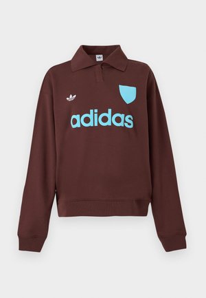 Ruskea sisäpuoli huppari, jossa on polo-kaulus, vaaleansininen "adidas" -logo ja kilpikoristelu, pehmeästä kankaasta valmistettu rento malli.