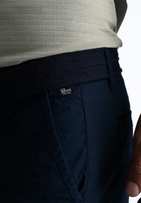 Pantaloni blu navy con una cintura elastica testurizzata e un piccolo etichetta del marchio. Il tessuto ha una finitura liscia con dettagli di cucitura visibili.