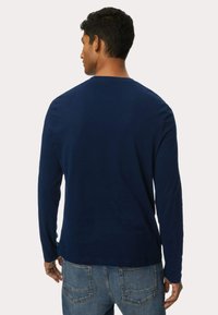 Langarmhemd in Marineblau aus Baumwolle, mit einem schlichten Design, weicher Textur und runder Ausschnitt. Von hinten gezeigt.