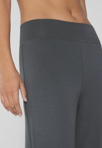 Dunkelgraue Leggings mit einem breiten Bund, aus glattem und dehnbarem Material, in einer stromlinienförmigen Passform und mit minimalen Nähdetails.
