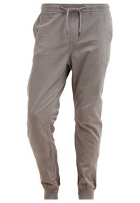 Pantalon de jogging marron clair effilé avec taille élastique, cordelette, poches latérales et poignets élastiques aux chevilles.
