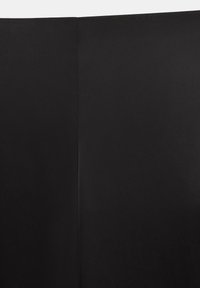 Gros plan d'un tissu noir avec une couture verticale au centre, montrant la texture et les détails de la couture.