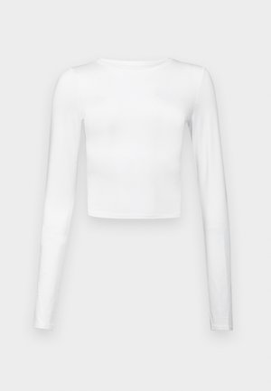Bílý dlouhý rukáv crop top z hladké, lehké látky s kulatým výstřihem a přiléhavým střihem. Žádné viditelné vzory nebo akcenty.
